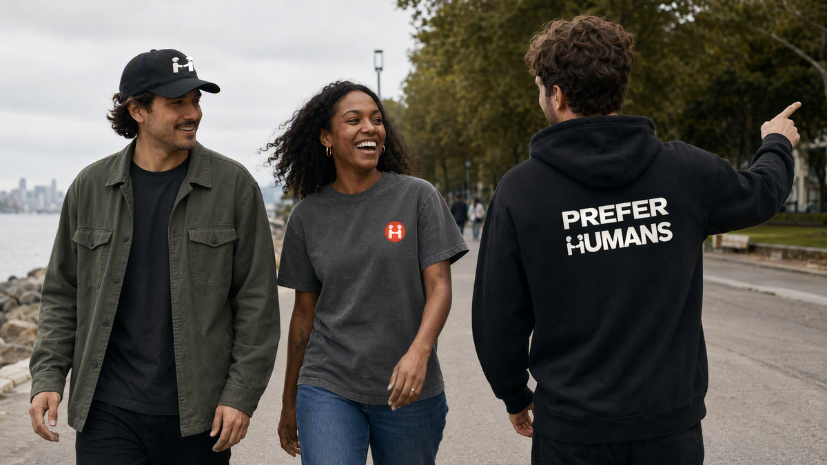 Three friends walking along a waterfront path: Human-H cap, PREFER HUMANS tee and the hoodie back print