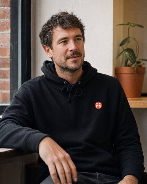 PREFER HUMANS hoodie worn by a man in a relaxed independent cafe setting