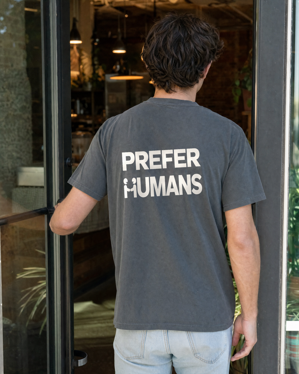 PREFER HUMANS tee back graphic in a cafe entrance lifestyle scene